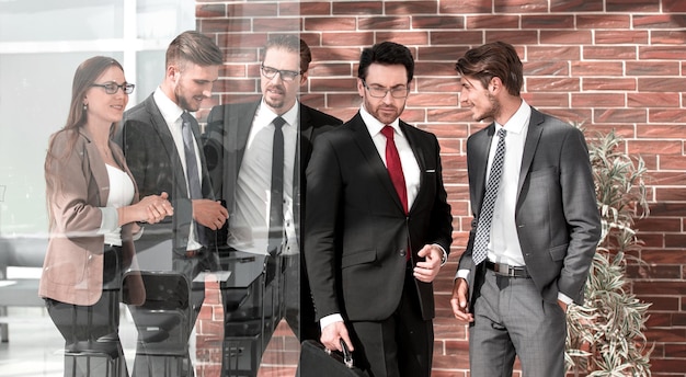 People standing in modern office behind glass wall