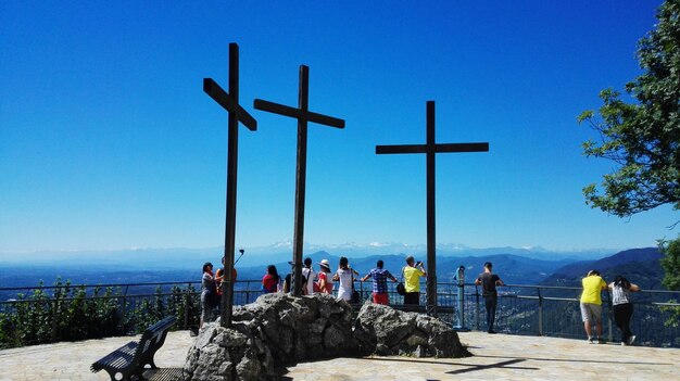 People standing at observation point against clear blue sky