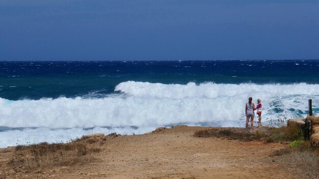 写真 浜辺の崖の上に立っている人々