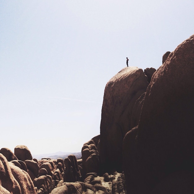 People standing on rocks against clear sky