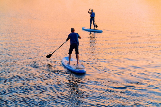 People standing up on Paddle boat on Galve Lake in Trakai in Lithuania. At sunset