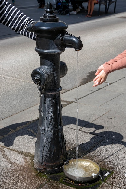 People on the street of Vienna drink water from a water column