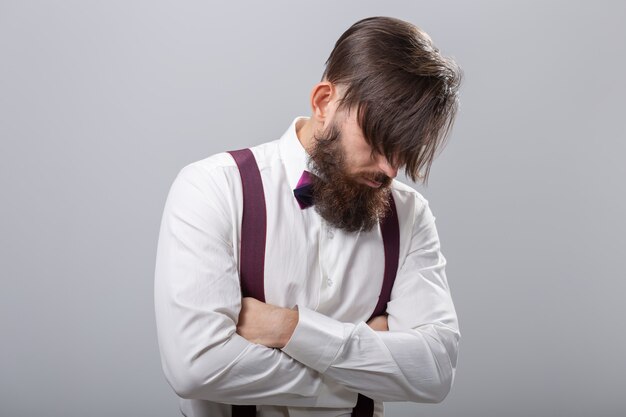 People, style and fashion concept - Portrait of bearded man dressed in white shirt over grey wall.