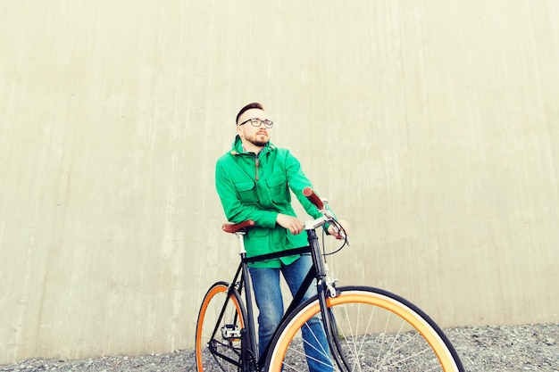 People, style, leisure and lifestyle - happy young hipster man with fixed gear bike on city street