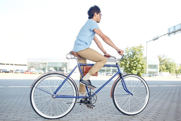 Photo people, style, leisure and lifestyle - young hipster man riding fixed gear bike on city street