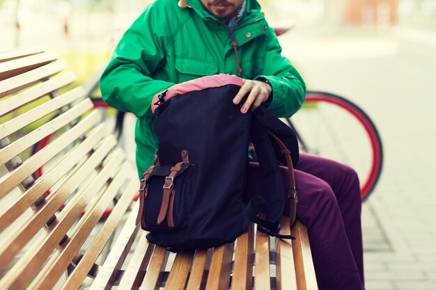 Фото Люди, стиль, туризм и образ жизни - крупный план человека с рюкзаком на городской скамейке