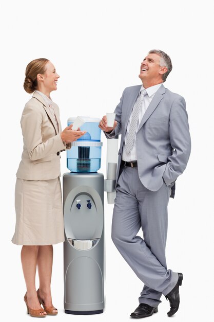 Photo people in suit laughing next to the water dispenser