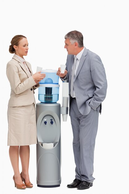 People in suit talking next to the water dispenser 