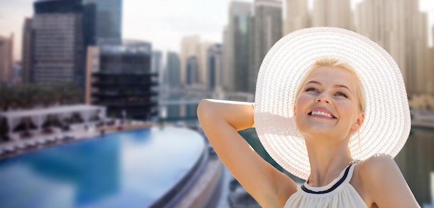 Foto persone, vacanze estive, viaggi, turismo e concetto di vacanza - bella donna in cappello da sole che si gode l'estate sullo sfondo della città di dubai