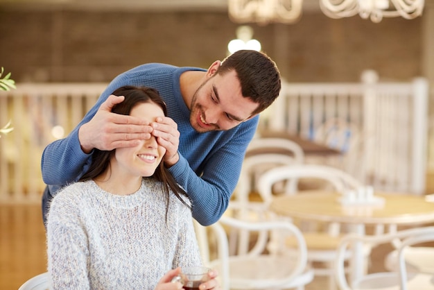 people, surprise and dating concept - happy couple drinking tea at cafe or restaurant