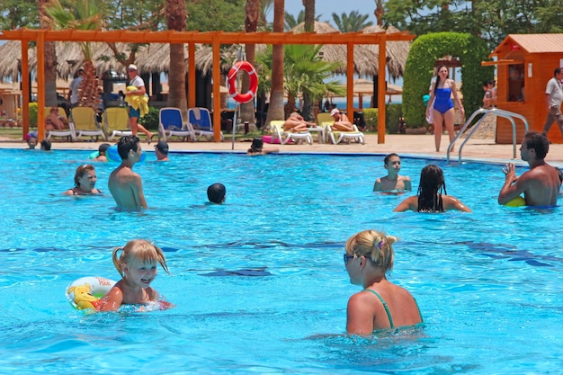 People swimming in pool of tropical resort Foreign tourists relax in Egyptian resort People enjoying summer vacations Beautiful view to swimming pool with transparent blue water