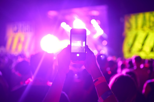 People taking photographs with smart phone during a music festival fans enjoying rock concert