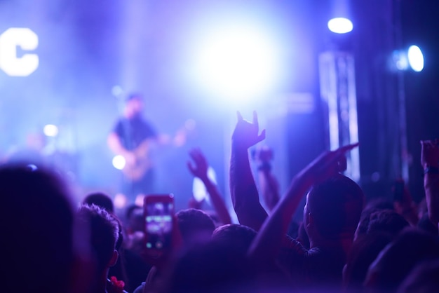 Люди фотографируют с помощью смартфонов во время музыкального фестиваля Фанаты наслаждаются рок-концертом