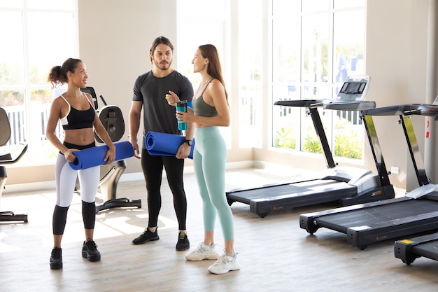 people talking and laughing together after a workout at gym. Fitness and healthy lifestyle concept.