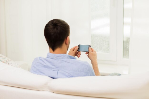 people, technology, communication and internet concept - close up of man with smartphone at home