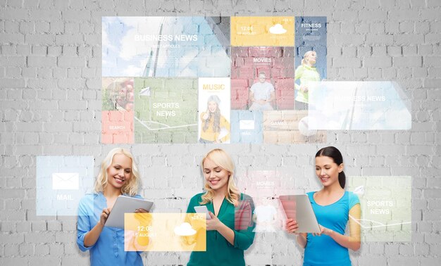 people, technology, communication and leisure concept - happy women with smartphone and tablet pc computers over gray brick wall background and media applications