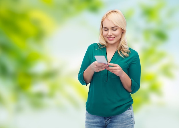 Foto concetto di persone, tecnologia, comunicazione e tempo libero - giovane donna felice con messaggio di testo sullo smartphone su sfondo verde naturale