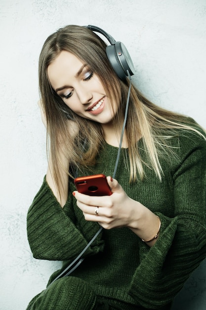 People and technology concept happy woman in headphones listening to music from smartphone