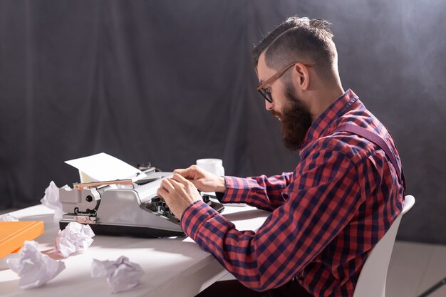 People and technology concept - Writer surrounded by scraps of paper focused on work.