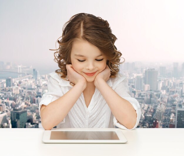 people, technology, education and children concept - happy smiling girl with tablet pc computer over city background