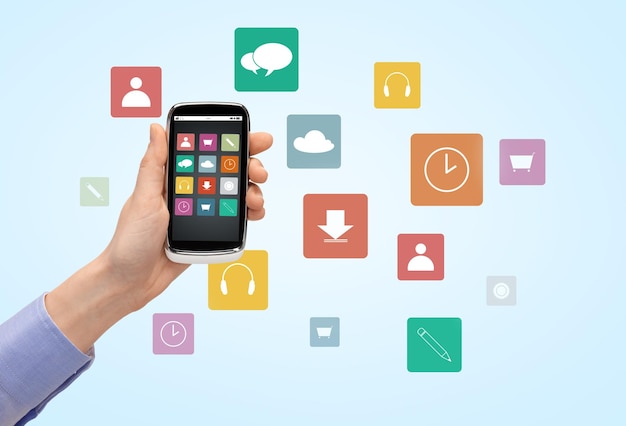 人、テクノロジー、メディアのコンセプト – 画面にアプリケーションのアイコンが表示されたスマートフォンを持つ女性の手の接写