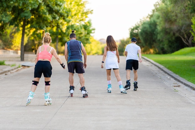 People on their backs skating with inline skates in a path of a park