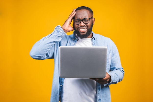 People and tiredness concept. Fatigue black African American man takes off spectacles, feels sleepy and overworked, surrounded with modern technologies.