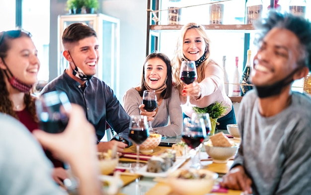 People toasting red wine at fashion restaurant bar with open face mask