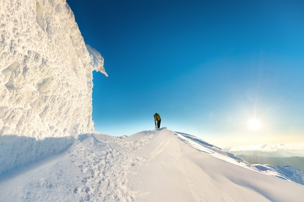 People on the top of the winter mountain in snow at sunset