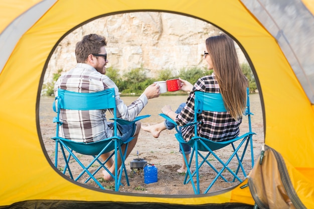 People, tourism and nature concept - Cute couple sitting near yellow tent.