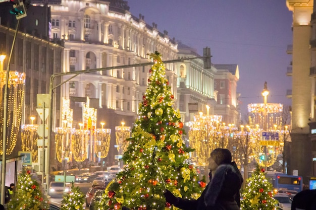 People and tourists walk along street decorated for Christmas