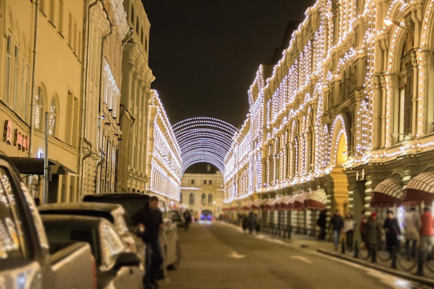 People and tourists walk along street decorated for New Year and Christmas