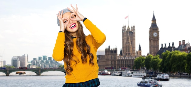 Foto concetto di persone, viaggi, turismo e moda - giovane donna felice o ragazza adolescente in abiti casual e cappello hipster che si diverte sul ponte sul tamigi e sul big ben sullo sfondo della città di londra