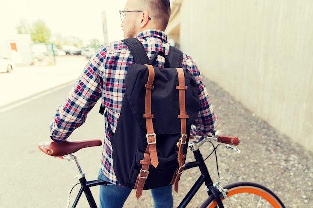 люди, путешествия, туризм, отдых и образ жизни - молодой хипстер с фиксированным велосипедом и рюкзаком на городской улице