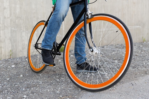 people, travel, tourism, transport and lifestyle - close up of young hipster man with fixed gear bike on city street