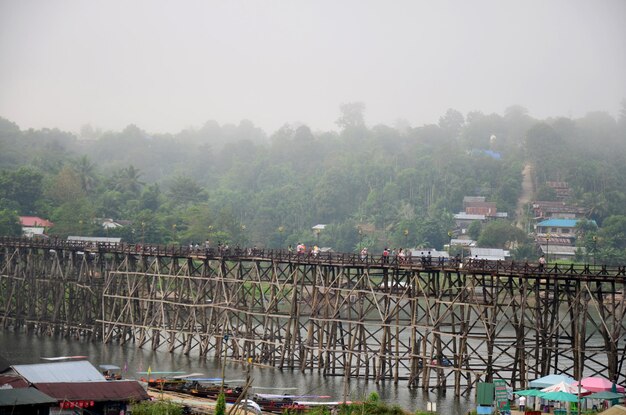 People travel and walk on Saphan Mon wooden bridge in morning time at Sangkhlaburi on December 4 2015 in Kanchanaburi Thailand