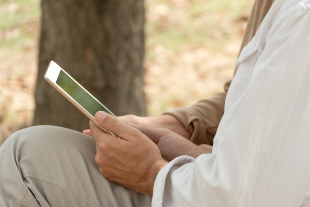 Persone che utilizzano tavoletta digitale seduta su una panchina nel parco