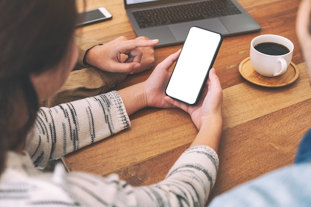 People using and looking at the same mockup mobile phone on wooden table together