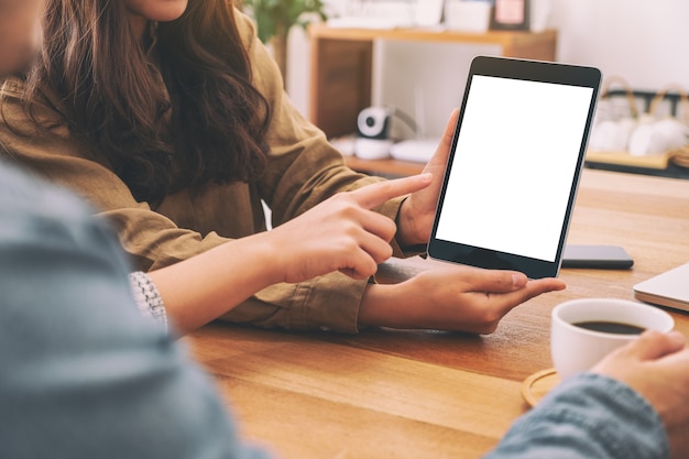 People using and looking at the same mockup tablet pc on wooden table together