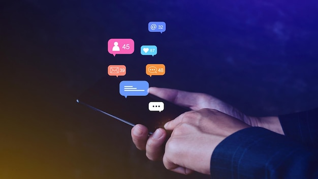 携帯電話でソーシャル メディアやデジタル オンライン マーケティングの概念を使用し、スマートフォンの画面に通知メッセージのコメントなどのアイコンを表示する人々
