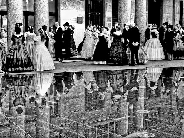 people waiting outside building wearing traditional dress