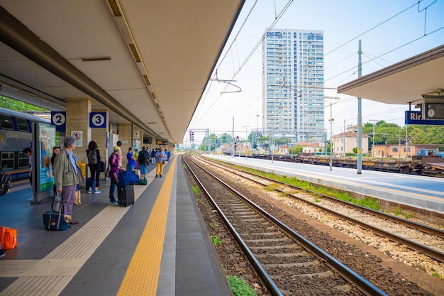 People waiting at railroad station in city against sky