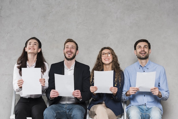 People waiting for their job interviews and holding blank papers