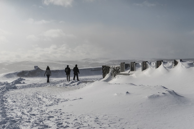 People walk along the snow-covered field on the background of the mountain