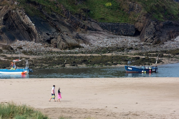 People walking across the sand by Bude Harbour