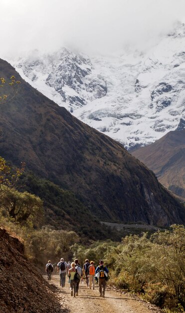 People walking against snowcapped mountains