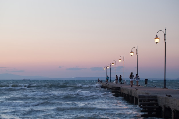 People walking along the pier in evening