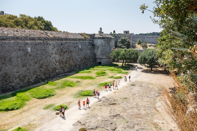 People walking around the walls of Medieval castle in old town of Rhodes island Greece