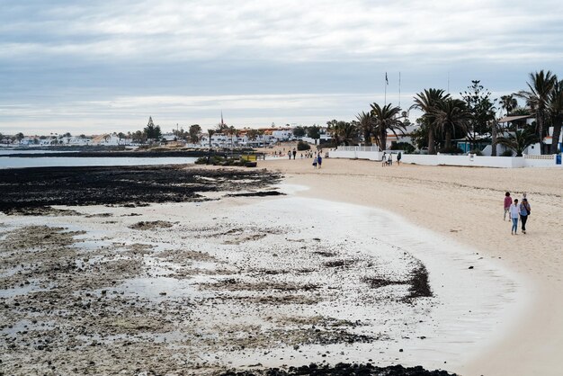 Photo people walking at beach against sky