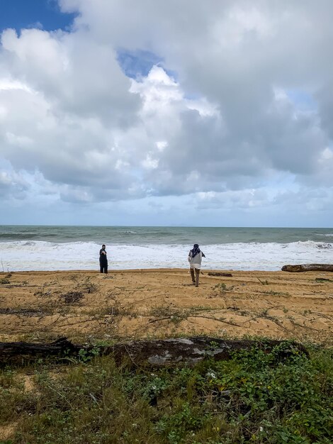 Foto gente che cammina sulla spiaggia contro il cielo